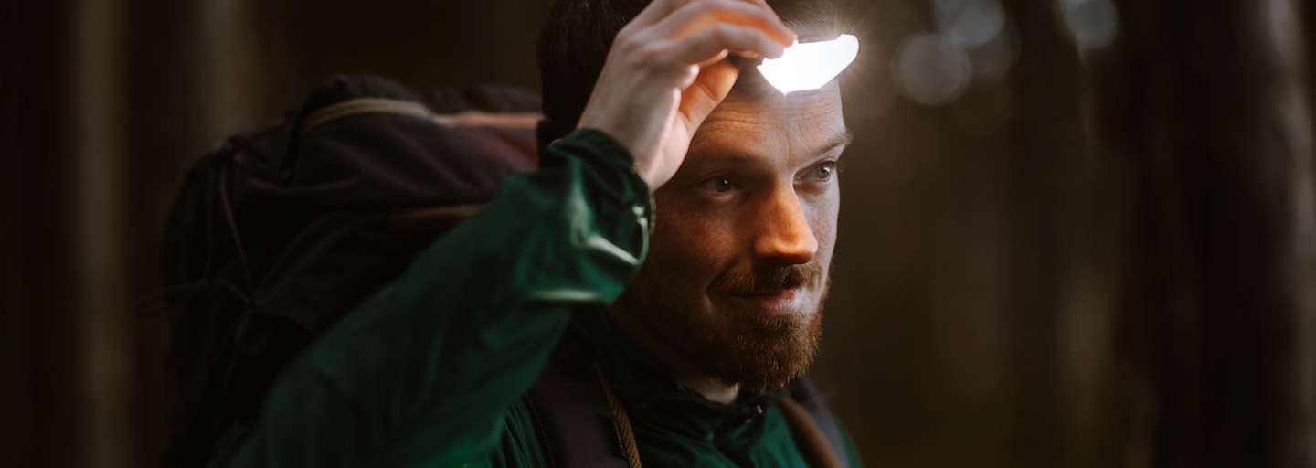 Mann ist in der Natur und benutzt eine Stirnlampe für gute Sicht.