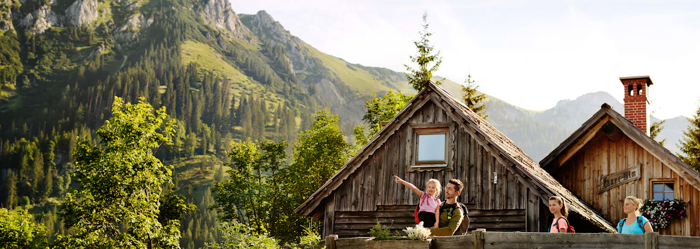 Eine Familie mit 2 Kindern steht auf einer Bergalm in der Steiermark im Sommer und beobachtet die Umgebung.