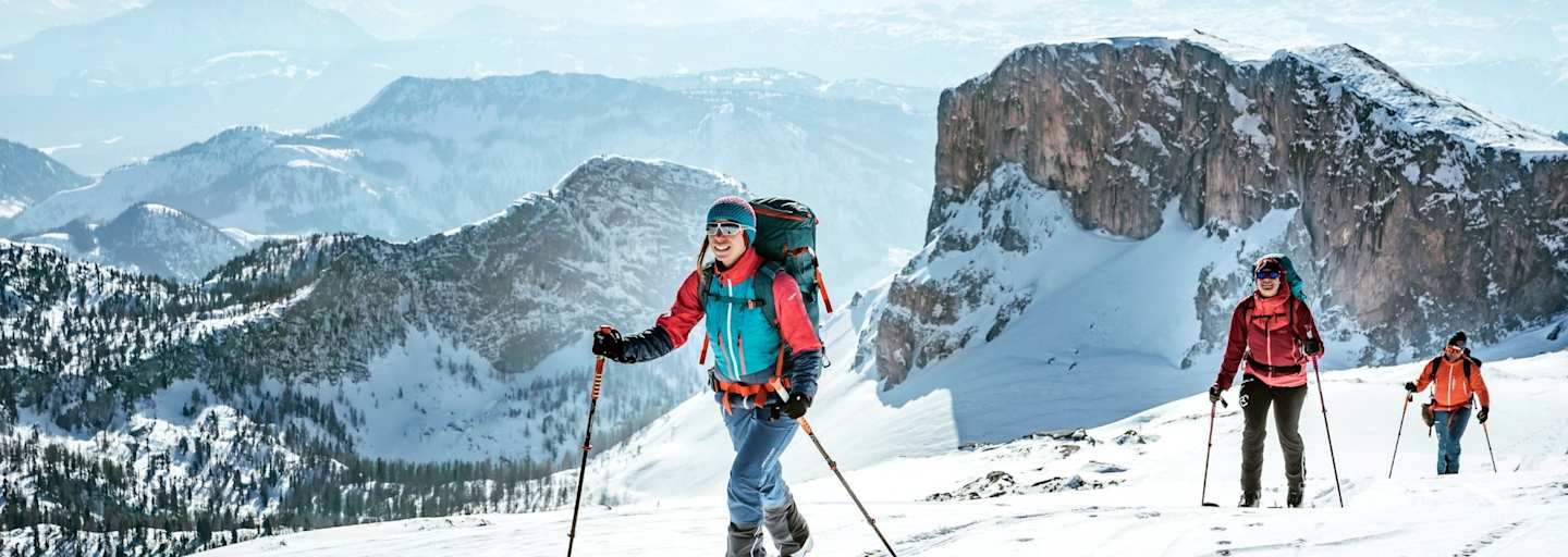 Sportler mit den Skiern am Weg zum Gipfel.