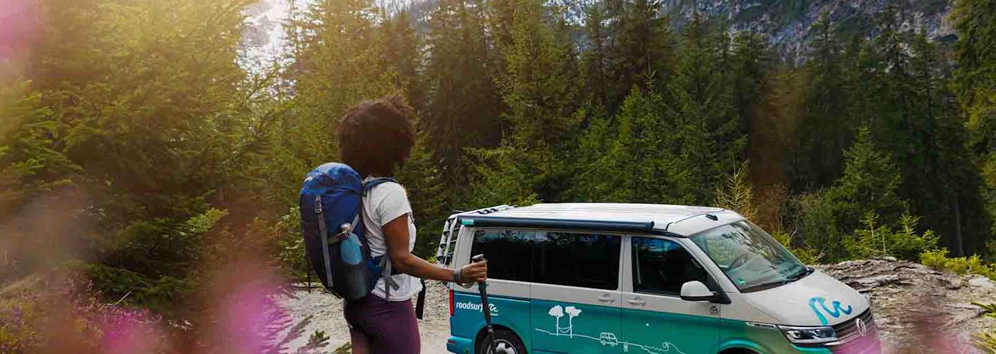Frau wandert durch die Alpen, unterwegs mit den roadsurfer Camper