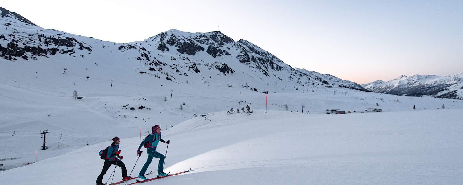 Skitourengeher auf der Skipiste am Abend