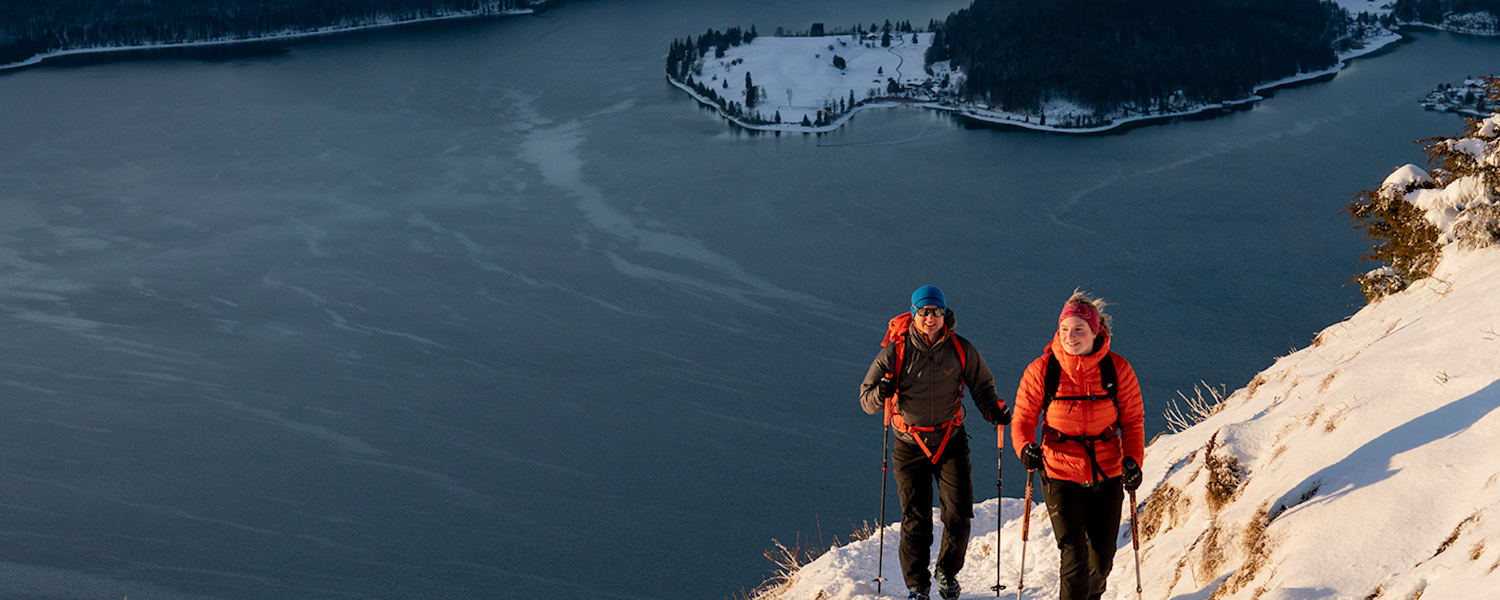 2 Personen gehen auf den Berg wandern im Winter mit Winterkleidung.