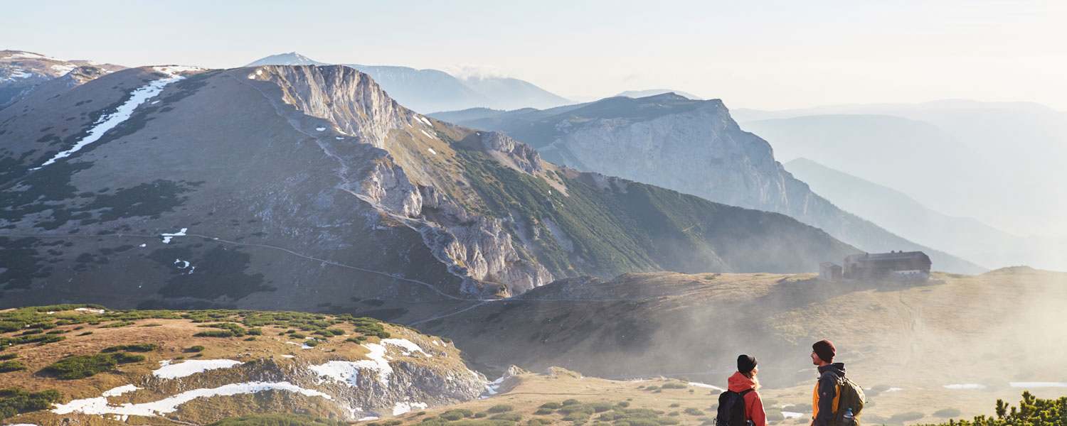 Morgennebel umspielt das Raxplateau beim Anstieg zur Heukuppe (2.007 m). Der Blick zurück wendet sich dem Karl Ludwig Haus und dem Predigtstuhl (li.) zu.