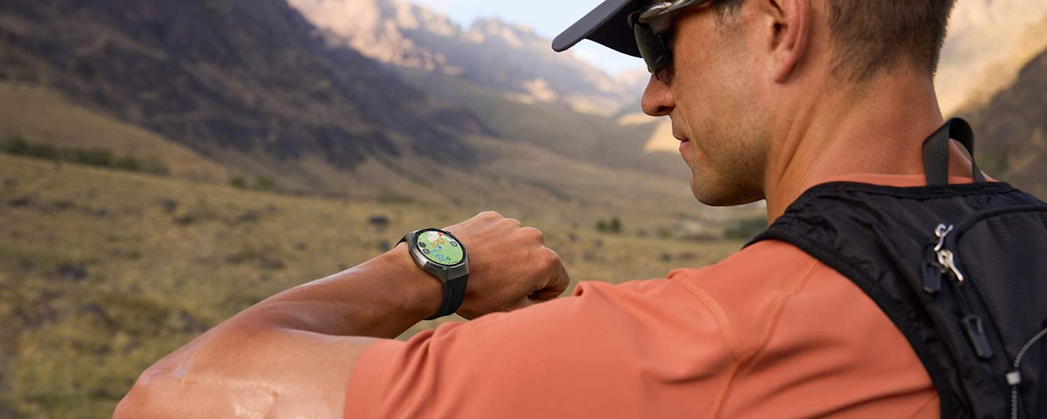 Outdoor-Sportler blickt auf seine HUAWEI WATCH GT 6 – präzises GPS-Tracking beim Laufen in den Bergen.