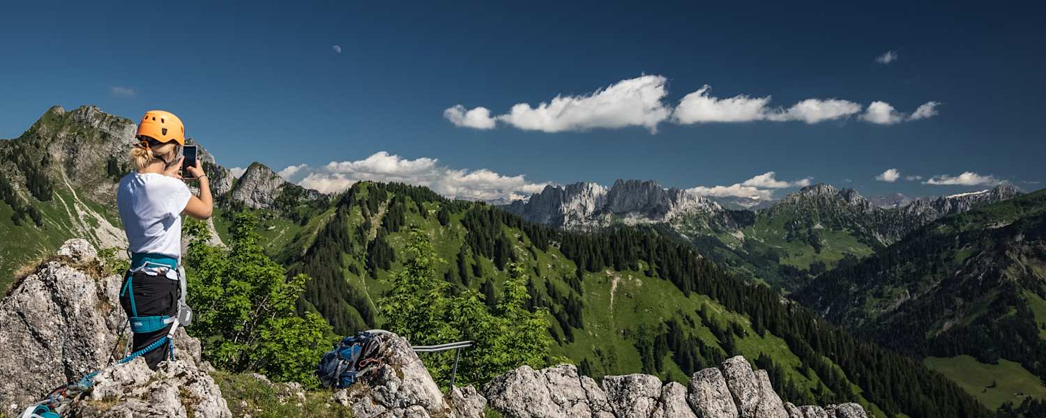 Eine Klettersteiggeherin macht am Ende der Via Ferrata Charmey im Kanton Freiburg ein Foto mit ihrem Handy.