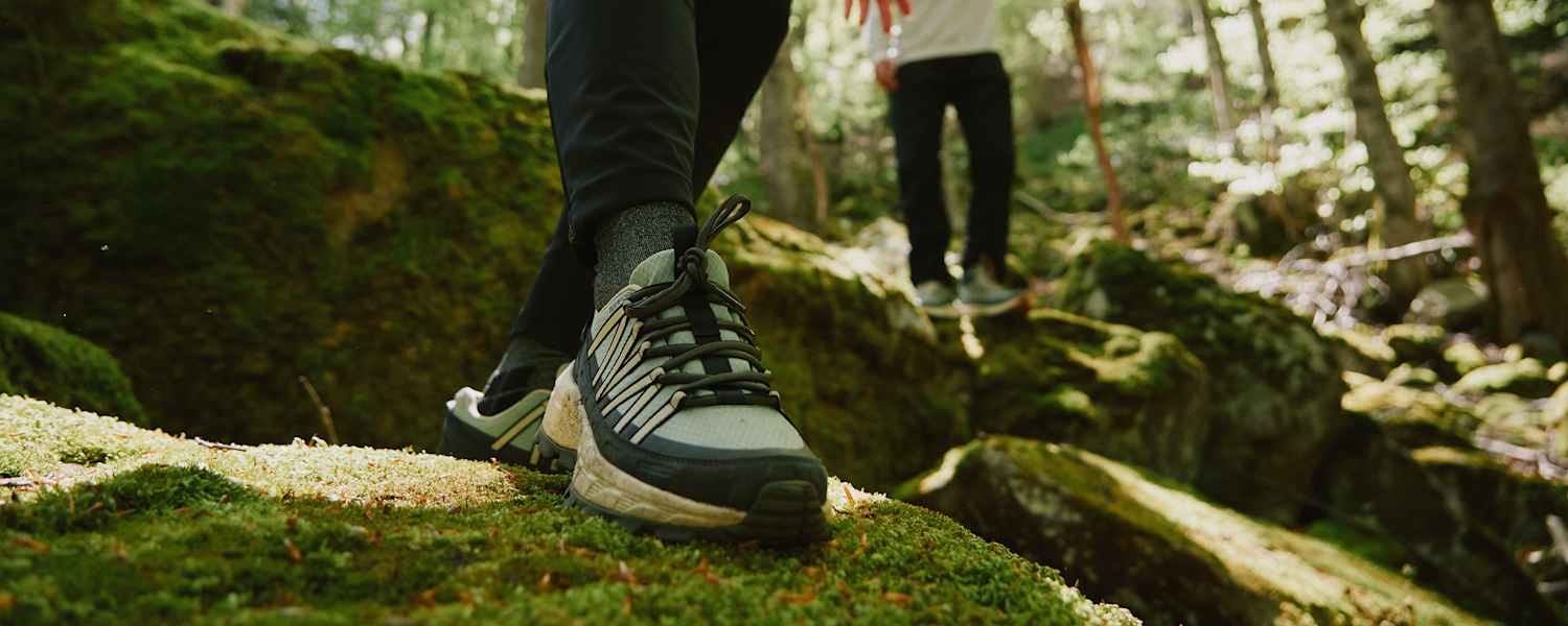 Der Wild Hike Wanderschuh von Jack Wolfskin auf bemoostem Stein in Wald.