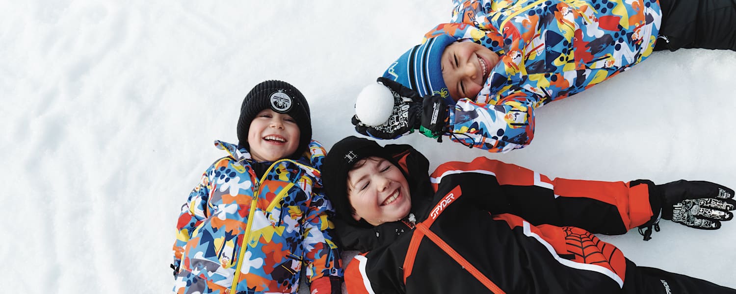 Drei Kinder liegen im Schnee in See.