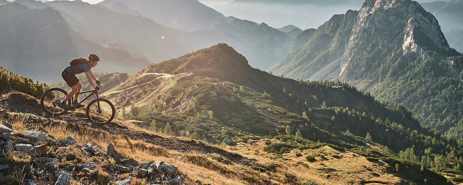 Abwärts in sanftem Licht: Mountainbiken mit Panoramablick.