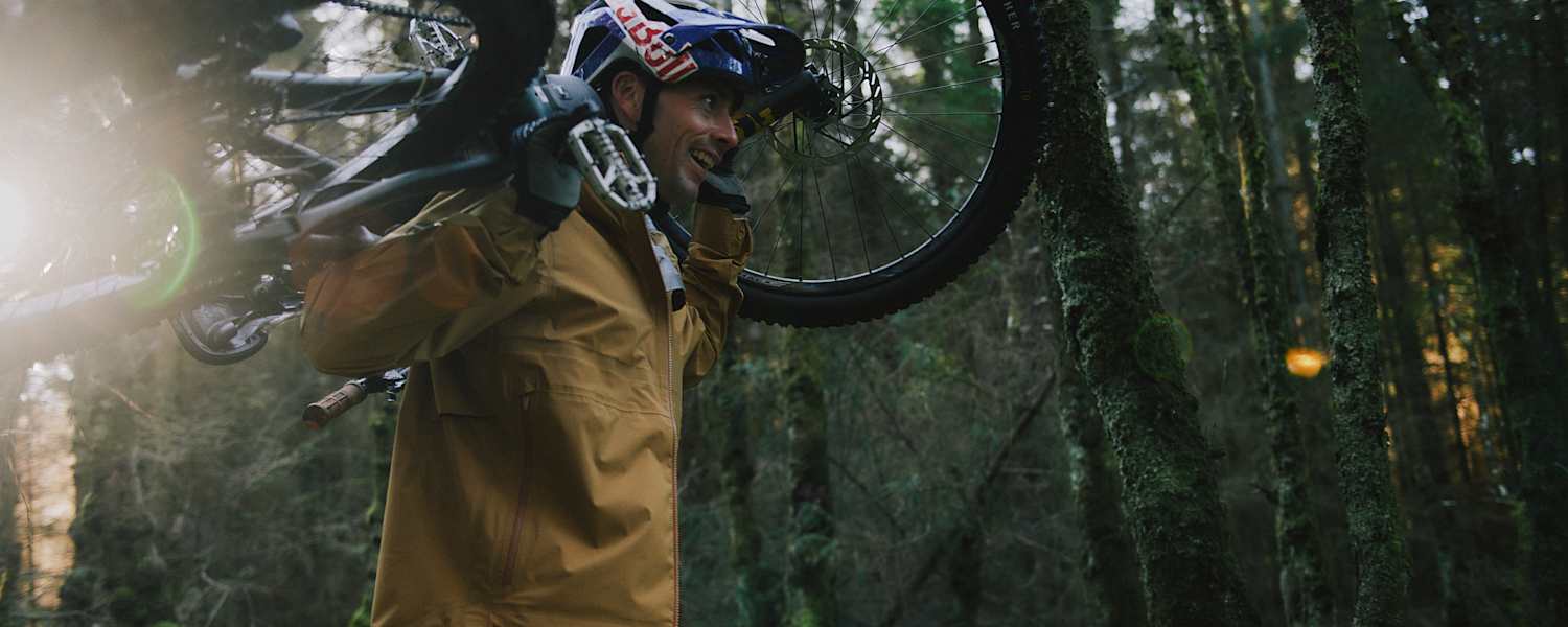 mann hat sein mountainbike auf den schultern, im wald