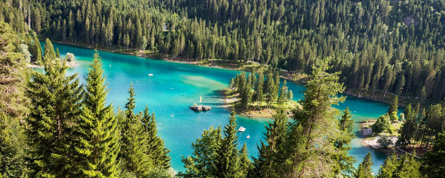 Ein See umgebene von Wäldern.