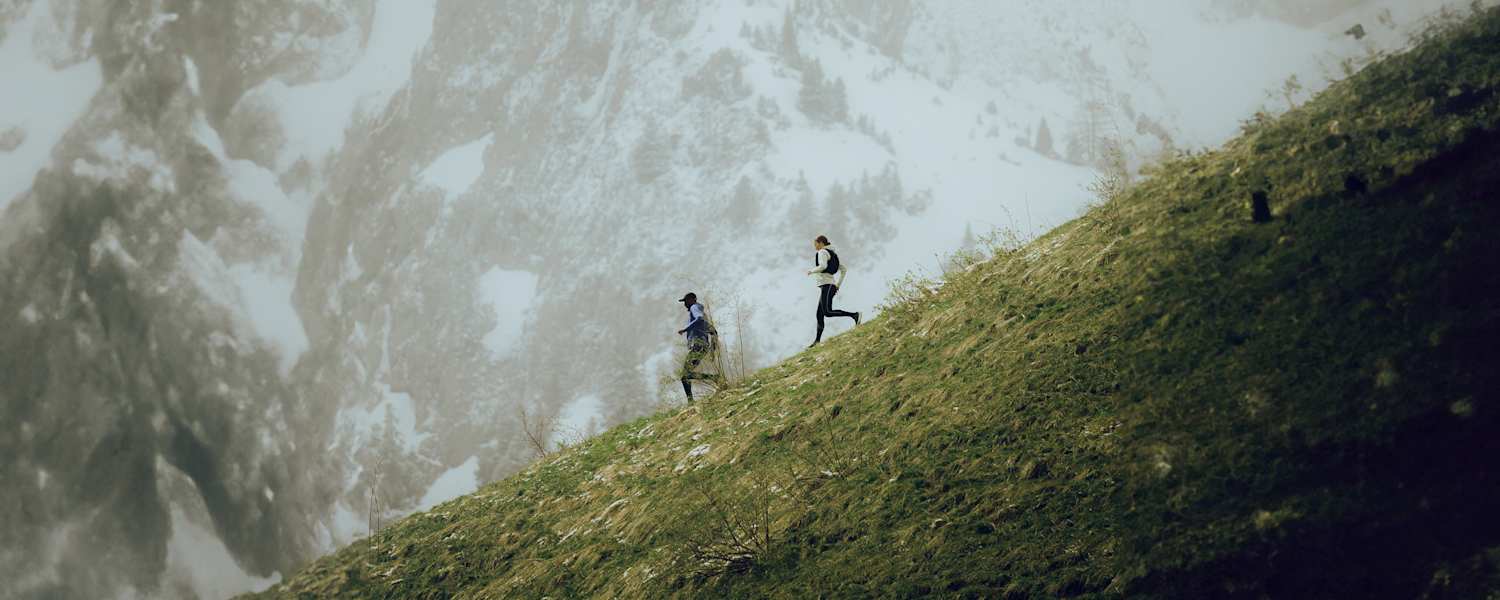 Zwei Trailerunner laufen mit der neuen Salomon Kollektion den Berg hinab.