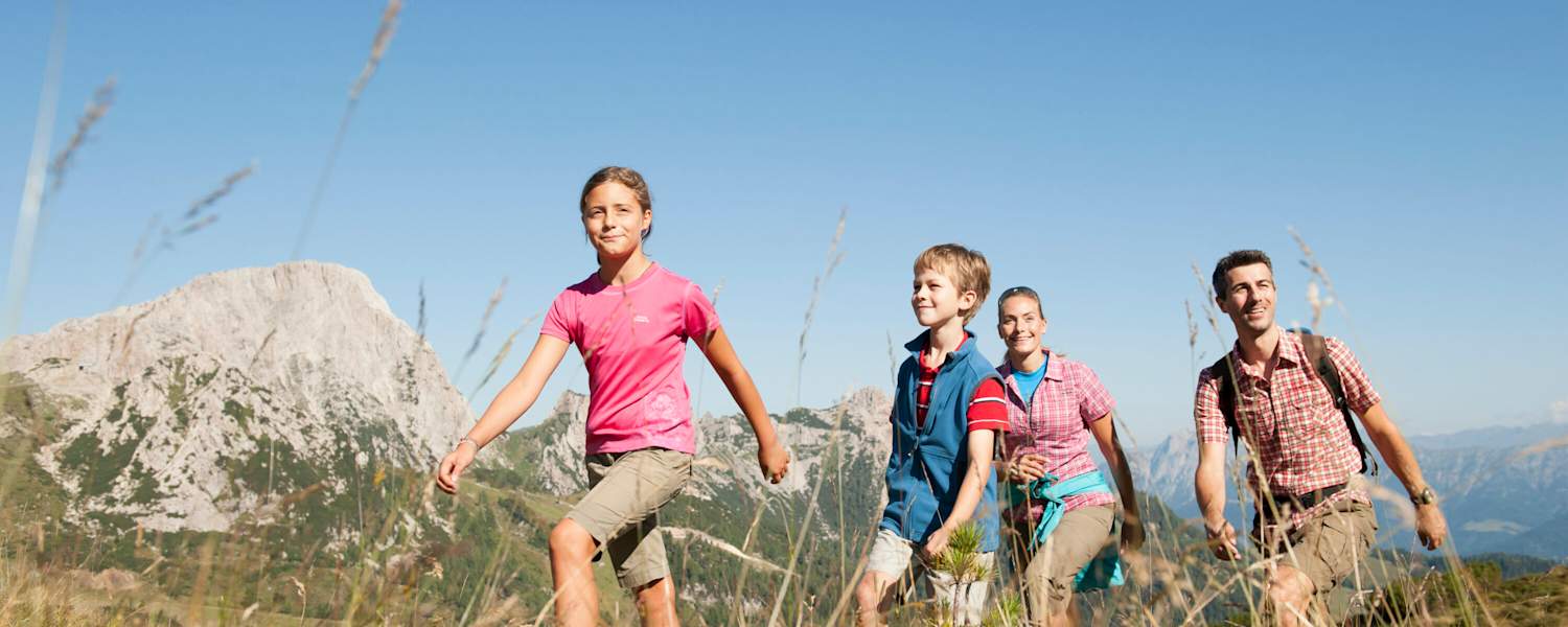 Eine Familie wandert auf einer Alm.