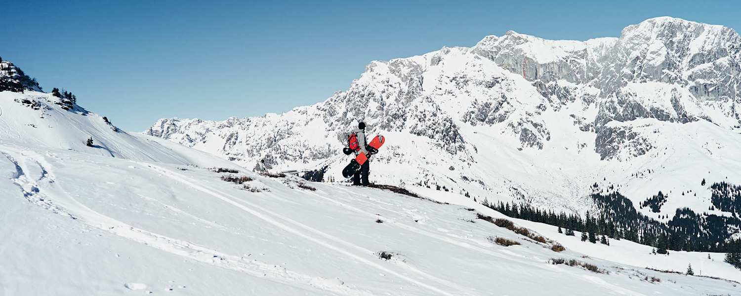 Ein Snowboarder steht in der Winterlandschaft mit Blick auf den Hochkönig.