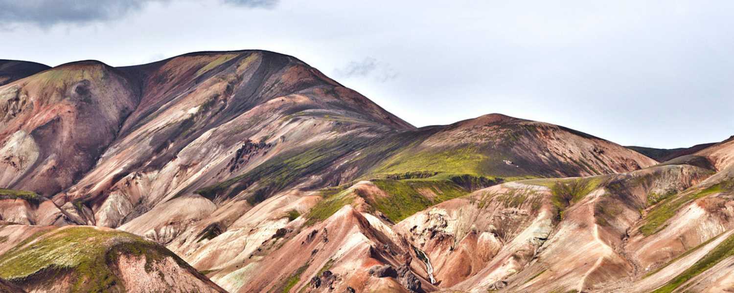 Landmannalaugar: Einsamer Wanderer in der Vulkanlandschaft von Landmannalaugar im Hochland. Buntes Rhyolith-Gestein teils mit Moos überwachsen.