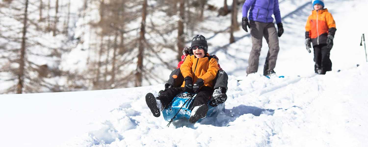 Zwei Kindern beim Bobfahren in der Natur.