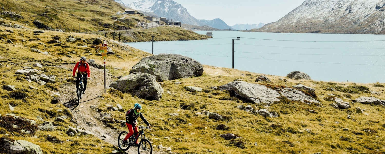Mountainbiker fahren neben einem See.