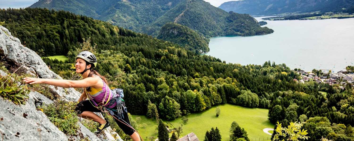 Manuela klettert am Plombergstein, im Hintergrund der türkise Wolfgangsee