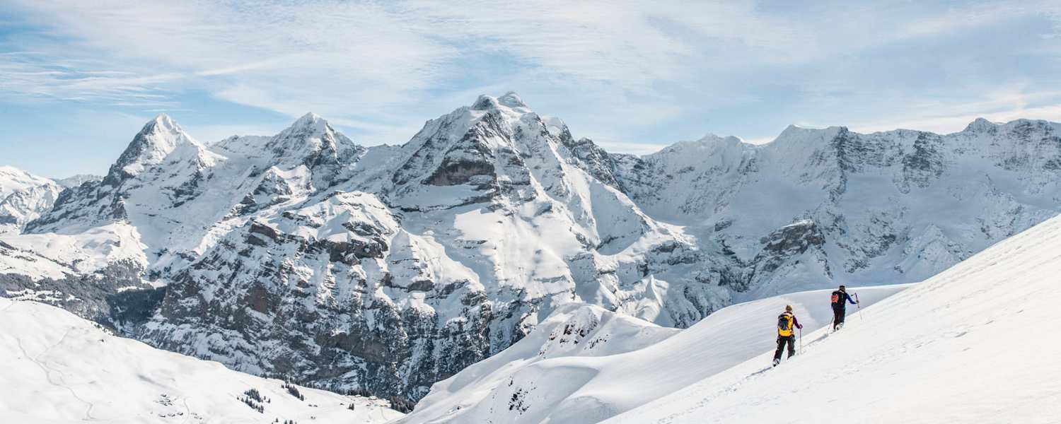 Zwei Schneeschuhwanderer vor atemberaubendem Bergpanorama.