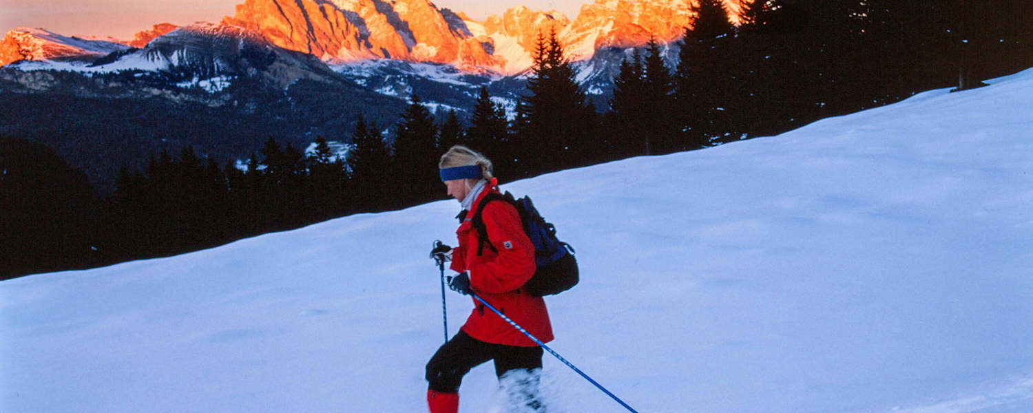 Alpenglühen: Schneeschuhwanderin vor Bergpanorama