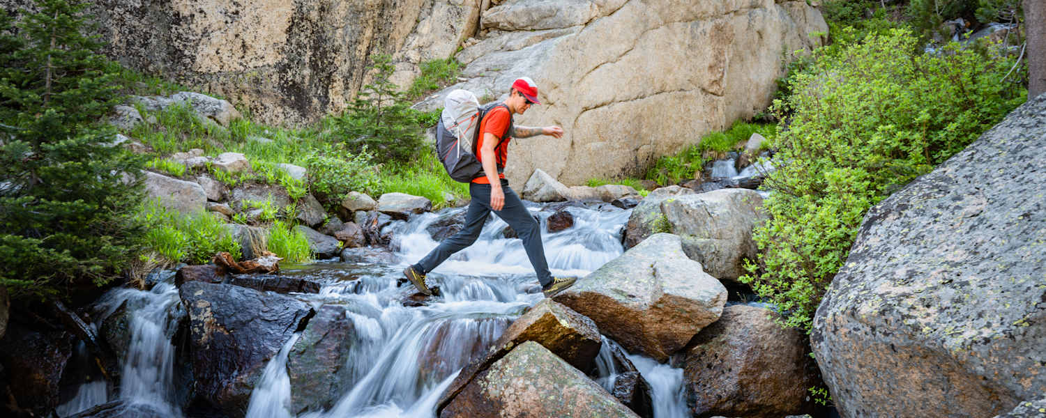 Rab Muon 50L Wanderrucksack mann geht über wasserfall