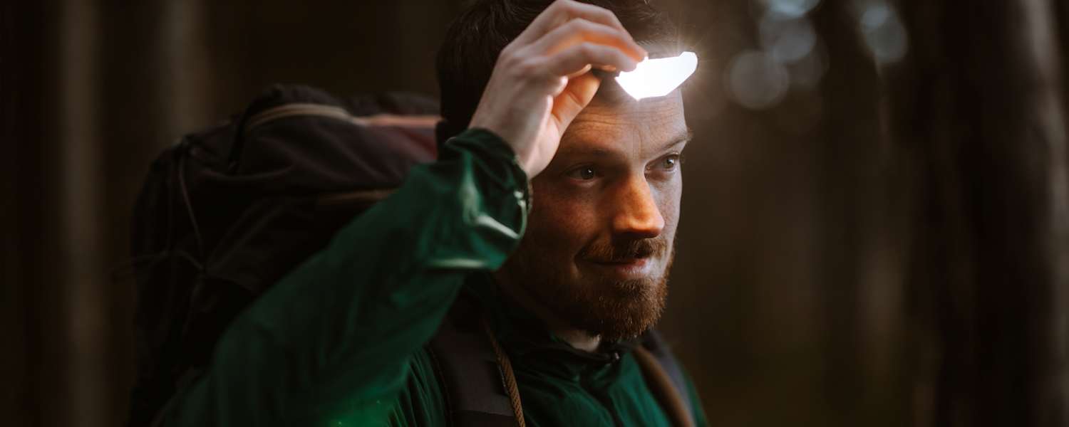 Mann ist in der Natur und benutzt eine Stirnlampe für gute Sicht.