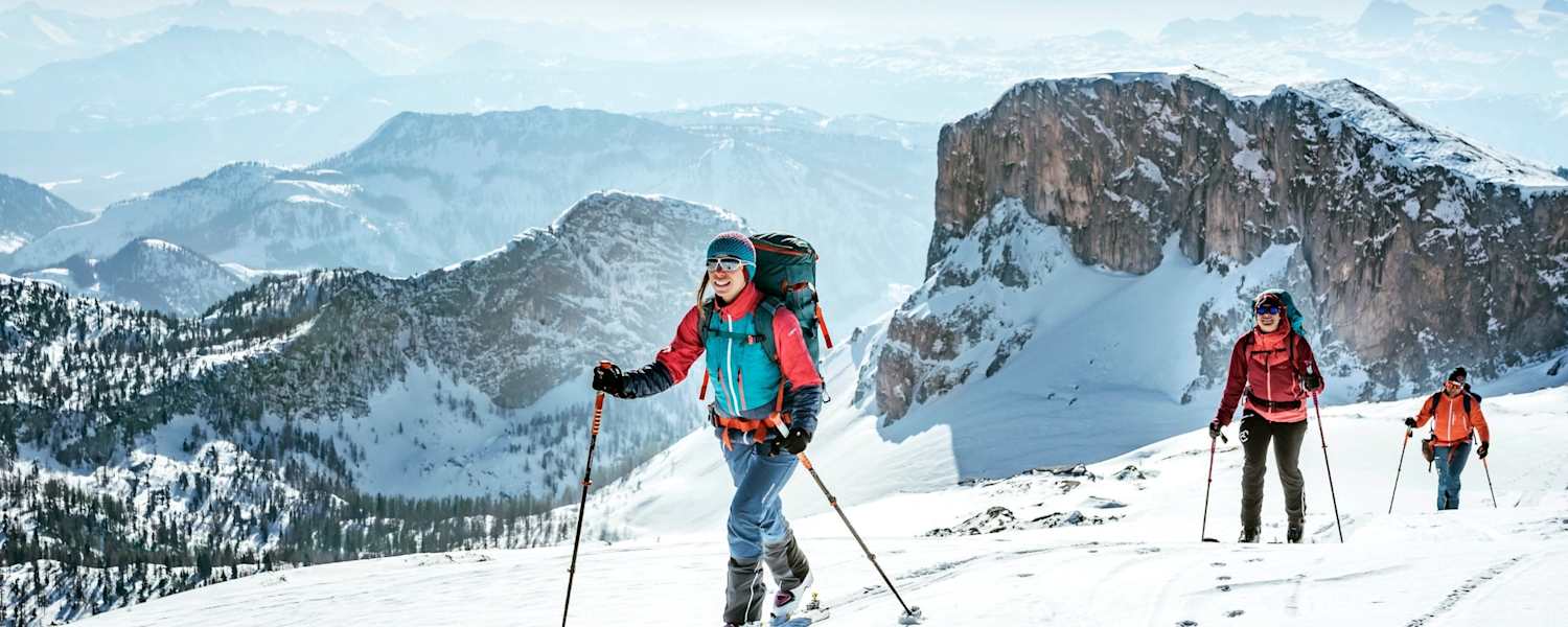Sportler mit den Skiern am Weg zum Gipfel.