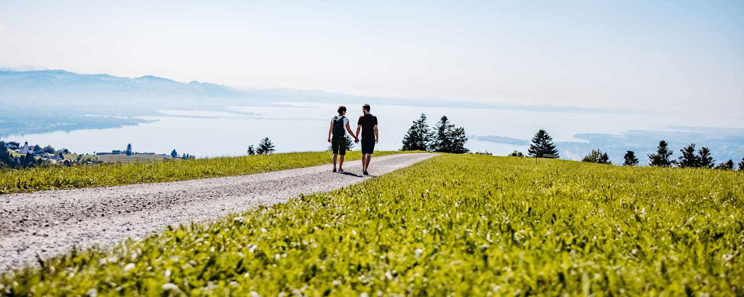 Ein Mann und eine Frau gehen Hand in Hand einen Wanderweg in Scheidegg entlang.