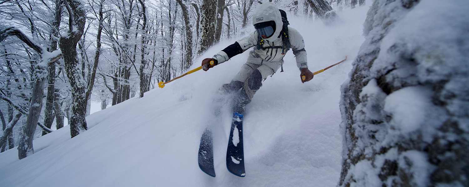Freerider im Tiefschnee zwischen winterlichen Bäumen.
