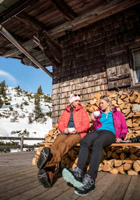 Zwei Frauen trinken Cappuccino vor einer Hütte