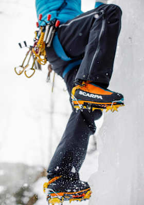 Die Beine des Kletteres, an den Füßen Steigeisen