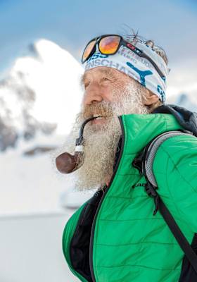 Hans Nindl mit seinem langen Bart, dahinter die Berge