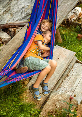 Zwei Kinder liegen in einer Hängematte und freuen sich.