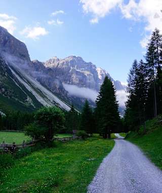 Im Flachstück des Pinnistals, kurz nach Passieren der Issenanger Alm. Die felsige Kirchdachspitze (2.840 m) im hinteren Talbereich hebt sich kontrastreich von den Bergwiesen ab. In Kürze wird der Habicht sichtbar.