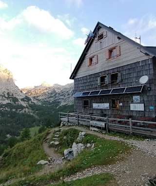 Vodnikov dom na Velem polju – dahinter das Triglav-Massiv und Mišelj vrh (li)