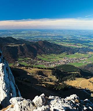 Blick vom Gipfel auf die dunklen Kaisersäle (links), Aschau und das Alpenvorland.