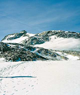 Markierungsstangen (in Bildmitte links) sind am Weg zum Hochkönig (Matrashaus) über steinige Bodenwellen und Firnmulden wertvolle Orientierungshilfen.