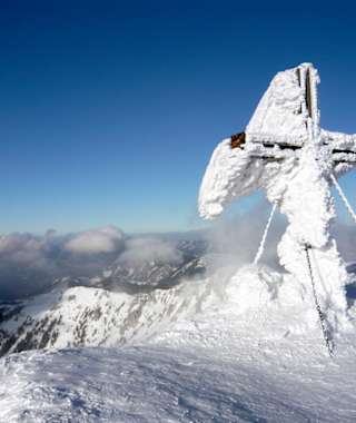 Das oft stark rauhreifüberzogene Gipfelkreuz auf der Hohen Veitsch, hinten links der Ötscher