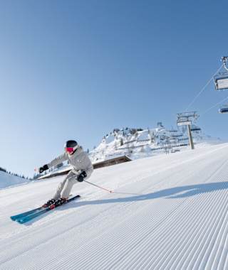 Ein Skifahrer carvt auf einer frisch präparierten Piste auf der Hermann Maier Tour im Snowspace Salzburg.