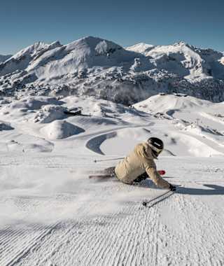 Ein Skifahrer carvt in hohem Tempo über die Pisten von Obertauern.