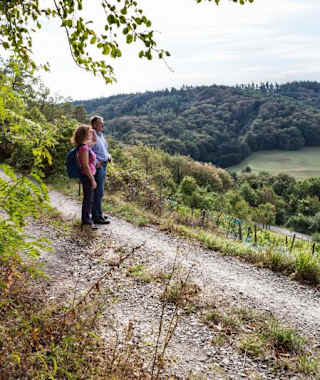 Ein Mann und eine Frau auf einem Feldweg, dahinter Landschaft