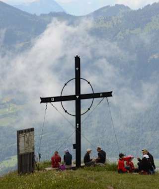 Wanderer geniessen den Gipfel des Gnipen mit dem Gipfelkreuz.