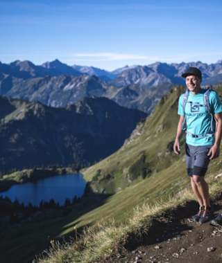 Zwei Wanderer vor einer schönen Berglandschaft mit einem blauen See.