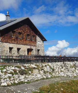 Eine Berghütte vor alpiner Kulisse.
