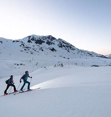 Skitourengeher auf der Skipiste am Abend