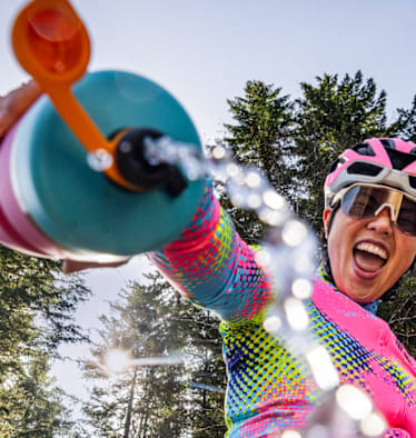 Radfahrerin mit Edelstahl-Trinkflasche von Bivo im Wald – plastikfreie, nachhaltige Hydration für Outdoor-Abenteuer.