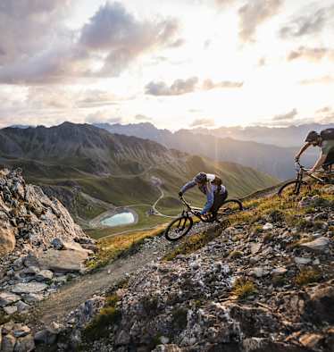Mountainbiker fahren in eindrucksvoller Gebirgslandschaft bergab