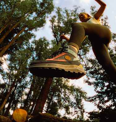 Frau springt im Wald über einen Baumstamm mit dem Hanwag Rotpunkt Light Mid GTX – leichter, vielseitiger Outdoor-Schuh für Alltag und Wanderungen