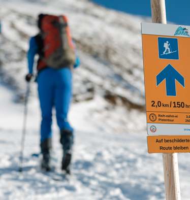 Das Pistentourenleitsystem des Landes Tirol mit orangen Hinweisschildern zeigt den sicheren Weg nach oben.