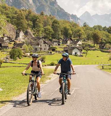 Zwei Fahrradfahrer fahren auf den gut ausgebauten Straßen im Kanton Tessin.