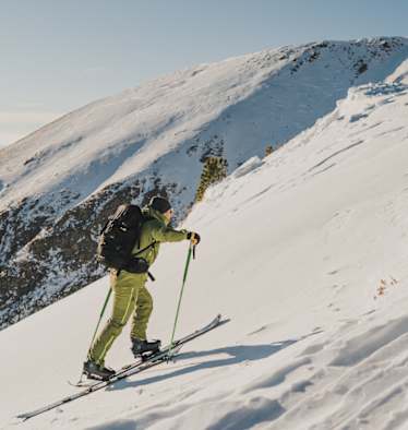 Immer am Boden bleiben: Wer die Ski bei jedem Schritt anhebt, verschenkt unnötig Energie. Viel effektiver: Ein gleichmäßiges Schlurfen. Und die g`schmackigen Salami Sticks von Loidl – sie liefern wertvolle Proteine und geben im Aufstieg Kraft.